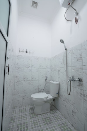 A small, white bathroom with a toilet, a shower, and tiled walls. - Sakura Guest House (Palembang)
