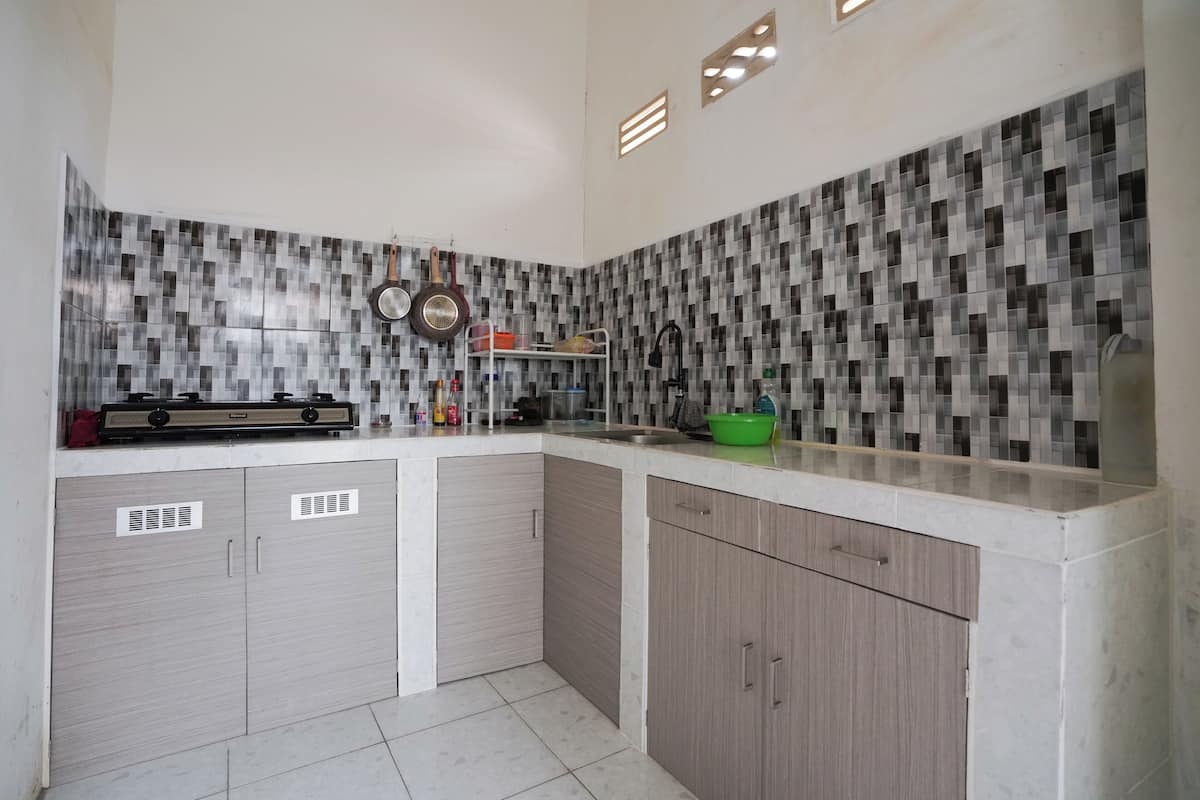 A kitchen with a tiled backsplash, a stove, and cabinets.