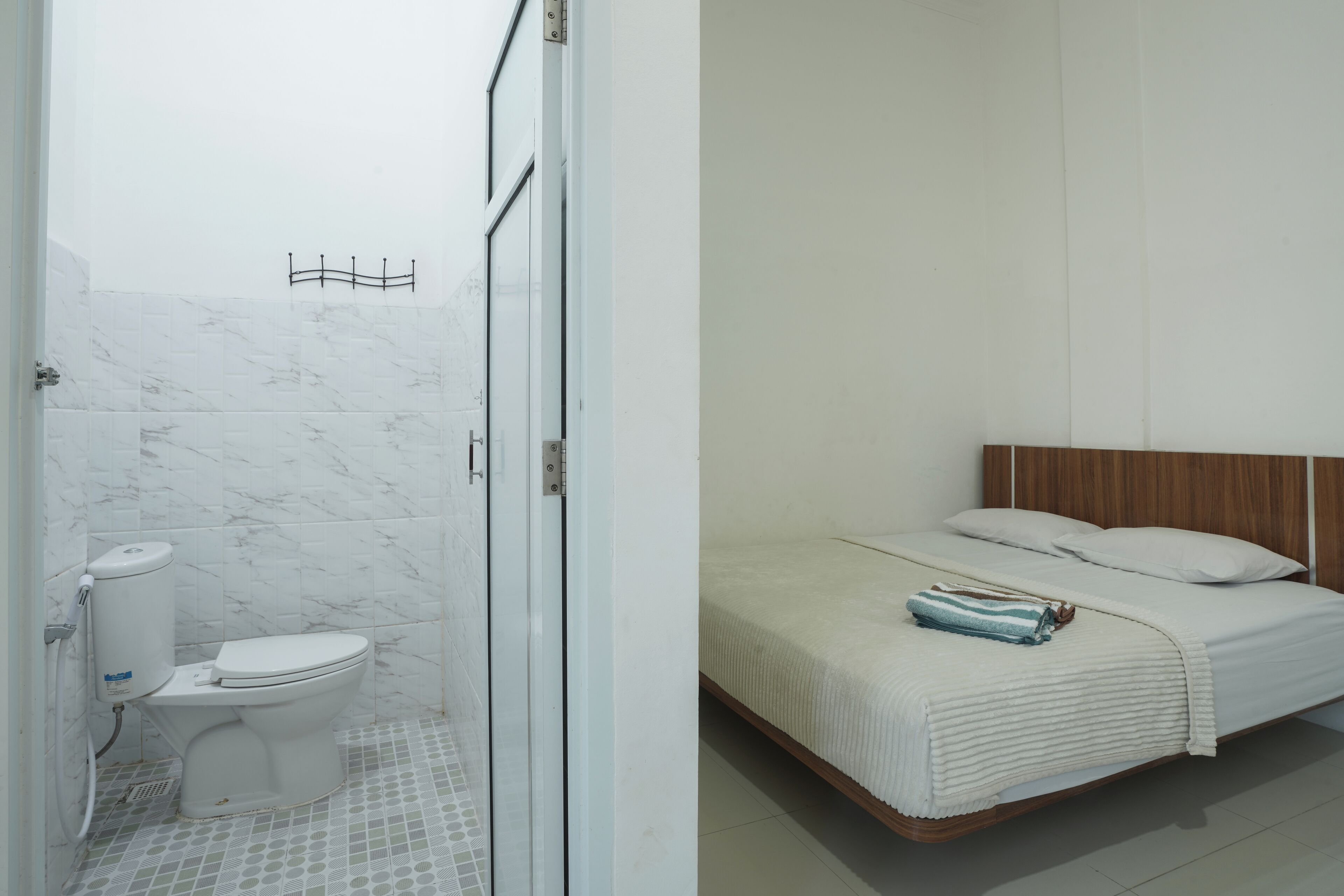 Une salle de bain avec des toilettes, une douche et un lit doté d’une tête de lit en bois.