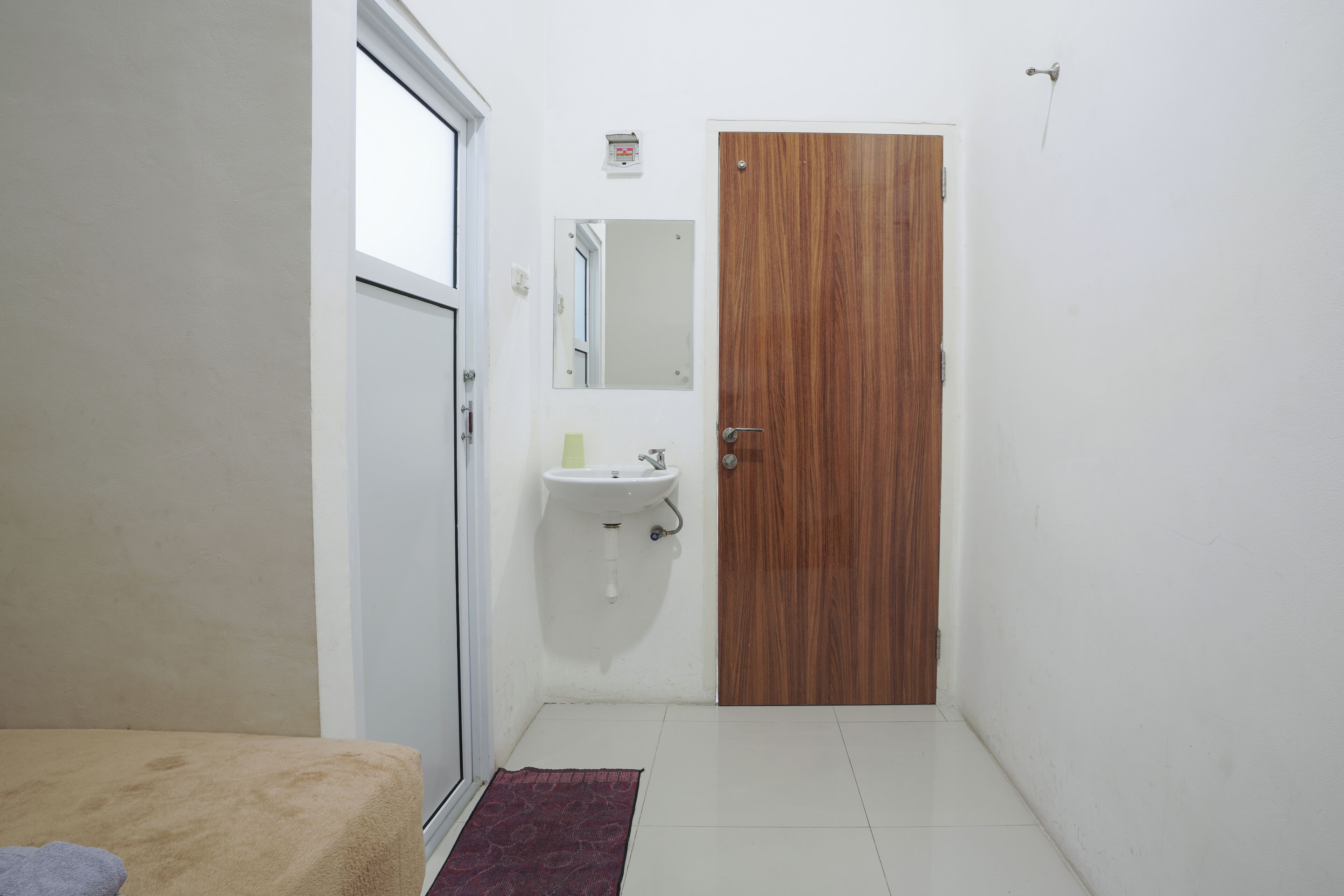 A small, clean room with a wooden door, a white sink, and a window.
