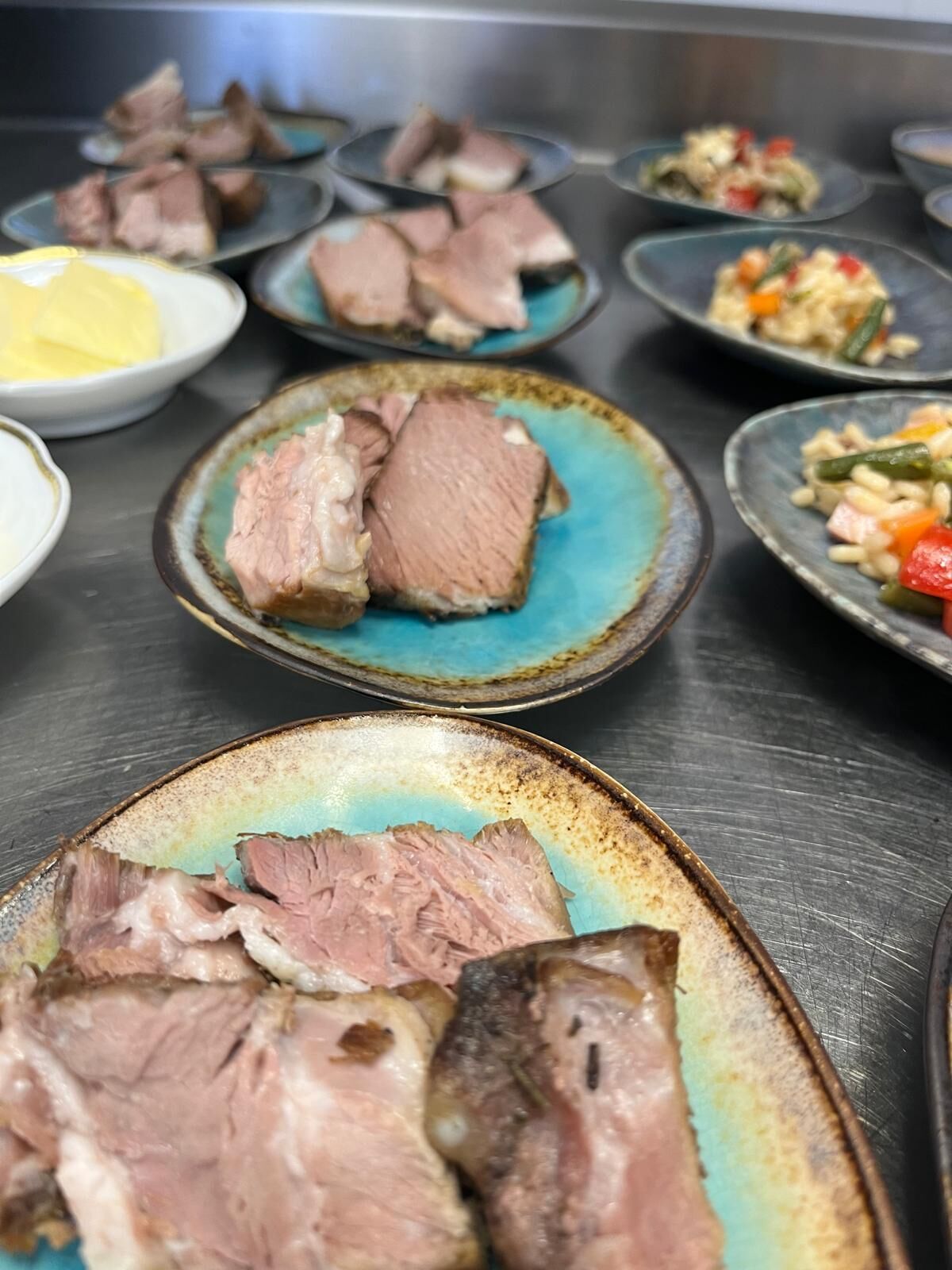 A variety of dishes, including sliced meat and vegetables, on ceramic plates.