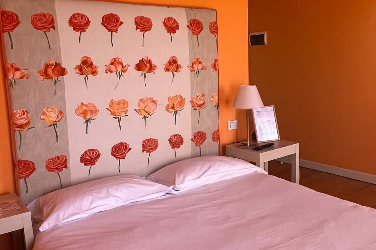 Een hotelkamer met een bed, nachtkastje, lamp en een ingelijst foto.