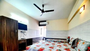 A bedroom with a bed, a ceiling fan, a TV, and a wardrobe.