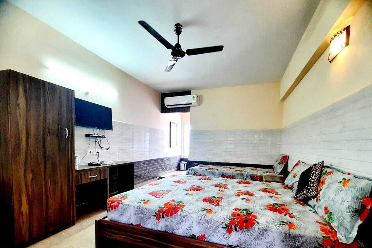 Une chambre à coucher avec un lit, un ventilateur de plafond, une télévision et une armoire.