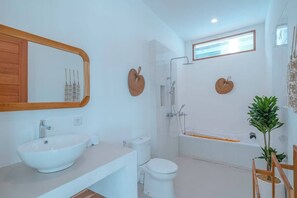 A modern bathroom with a large white sink, a toilet, a shower, and a bathtub.