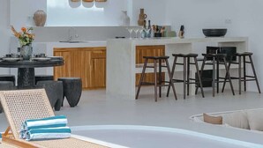 A modern kitchen with a central island, bar stools, and a dining area with a round table. - Villa 3BR Summary:<br>VI (pererenan)