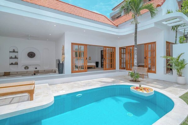 A modern house with a swimming pool, large windows, and a balcony.