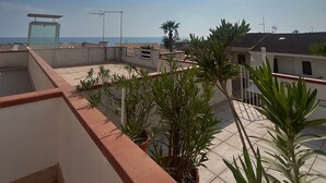 A rooftop terrace with potted plants, a clear view of the sea, and a sunny sky. - Sogno di Mare in Marina di Ragusa (Ragusa)
