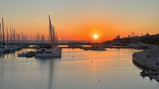 A marina at sunset with boats docked, a calm water surface, and a clear sky. - Sogno di Mare in Marina di Ragusa (Ragusa)
