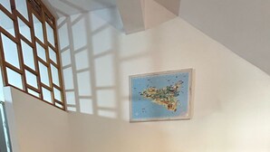 A room with a wooden table, two blue glasses, a bottle of wine, and a map on the wall. - Sogno di Mare in Marina di Ragusa (Ragusa)