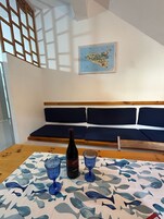 Una habitación con una mesa de madera, dos vasos azules, una botella de vino y un mapa en la pared.