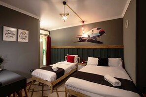 Een hotelkamer met twee bedden, een bureau en een wanddecoratie van een vliegtuig.