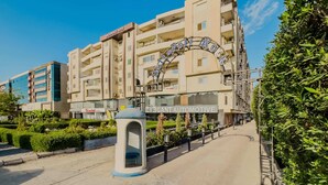 A multi-story hotel with a prominent curved entrance sign. - Xuru Stays I Heliopolis Rock (Cairo)