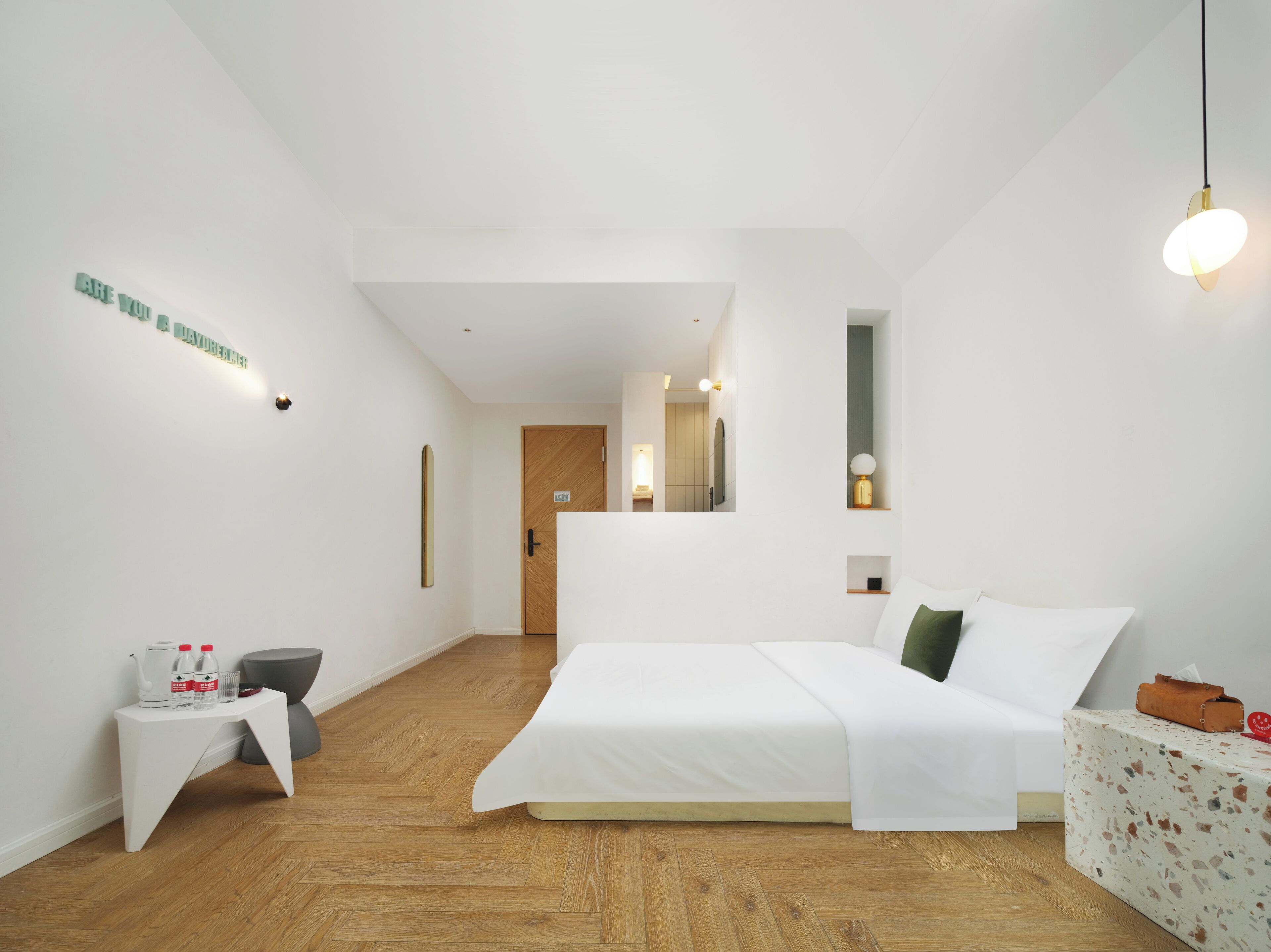 Ein modernes Hotelzimmer mit einem großen Bett, einem kleinen Nachttisch, einem Spiegel und Holzboden.