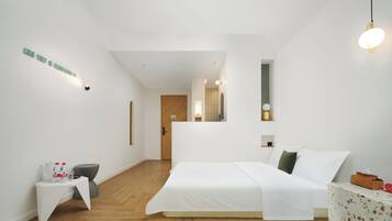Ein modernes Hotelzimmer mit einem großen Bett, einem kleinen Nachttisch, einem Spiegel und Holzboden.