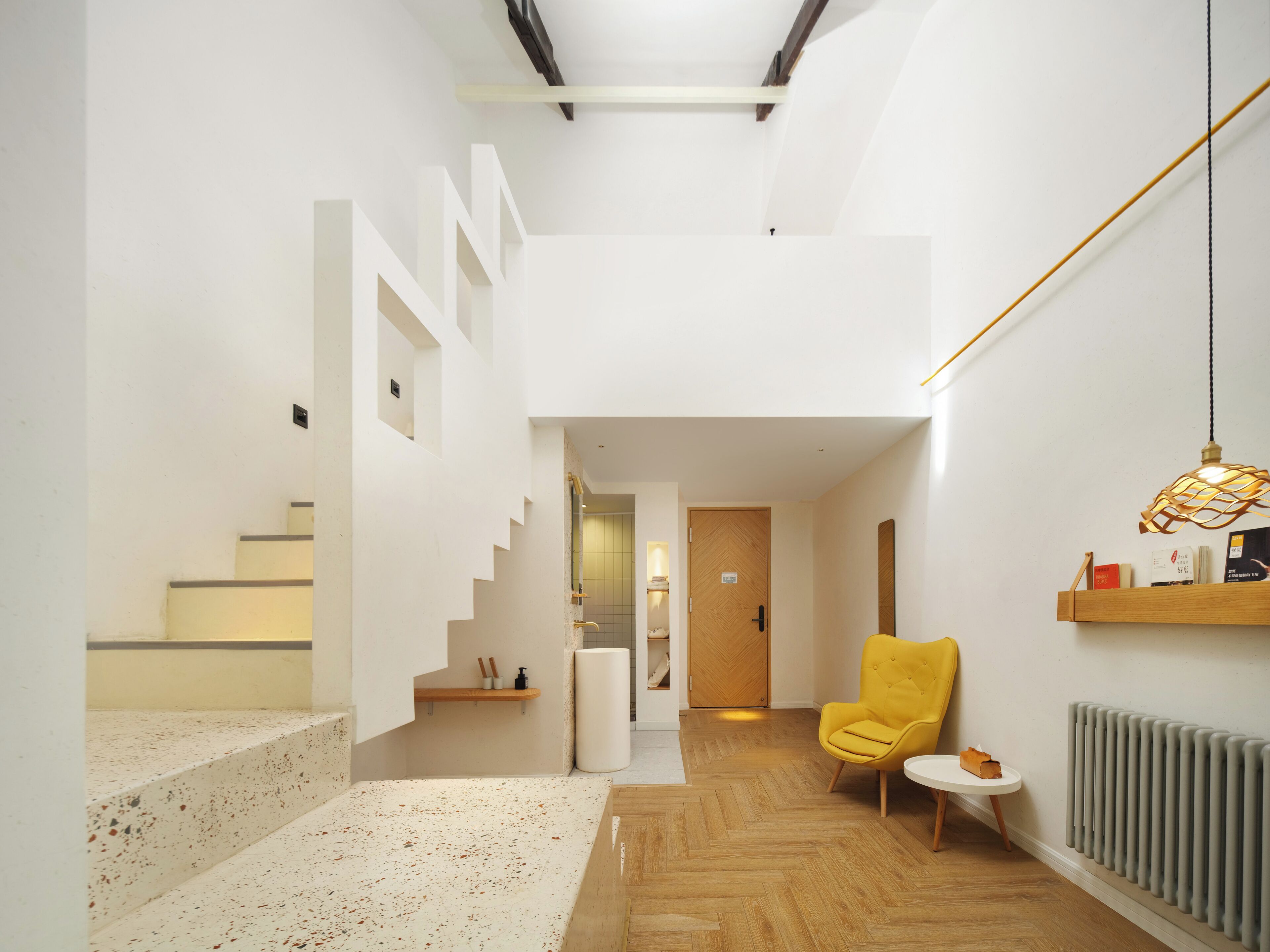 Un interior moderno con una escalera, un sillón amarillo y una pequeña mesa.