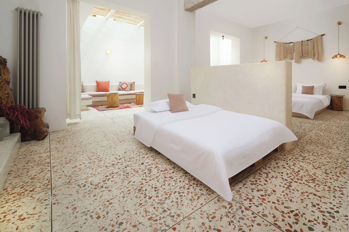 A modern hotel room with a large bed, a seating area with a sofa and a small table, and a view of the outside.