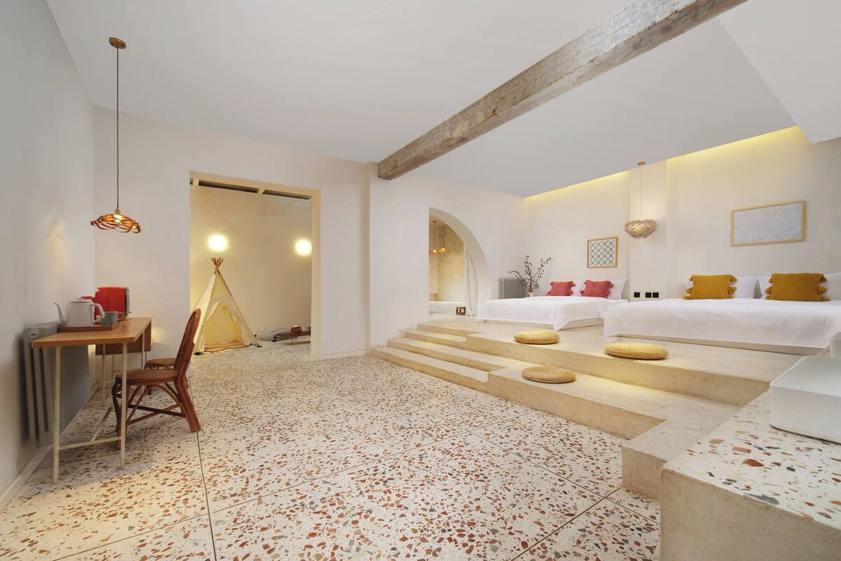 A spacious room with a large bed, a dining area with a table and chairs, and a cozy seating area with a chair and a small table.