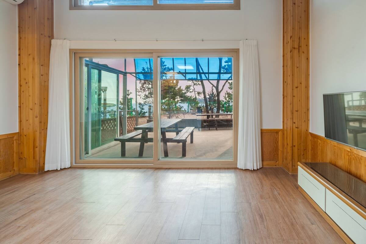 A spacious room with a large sliding glass door leading to an outdoor patio with wooden furniture.