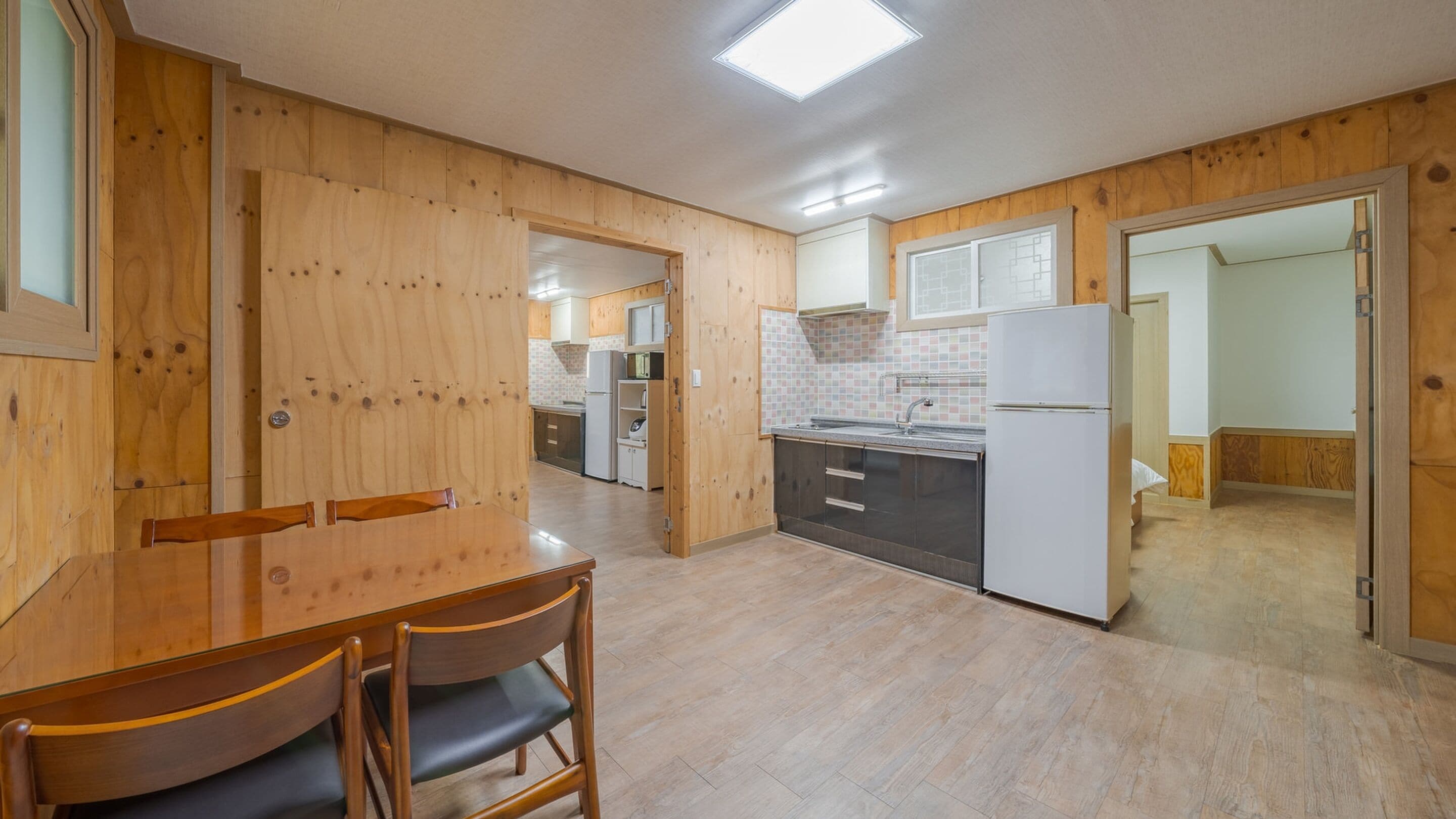 Une cuisine moderne avec des meubles en bois, une table à manger avec des chaises et un réfrigérateur.