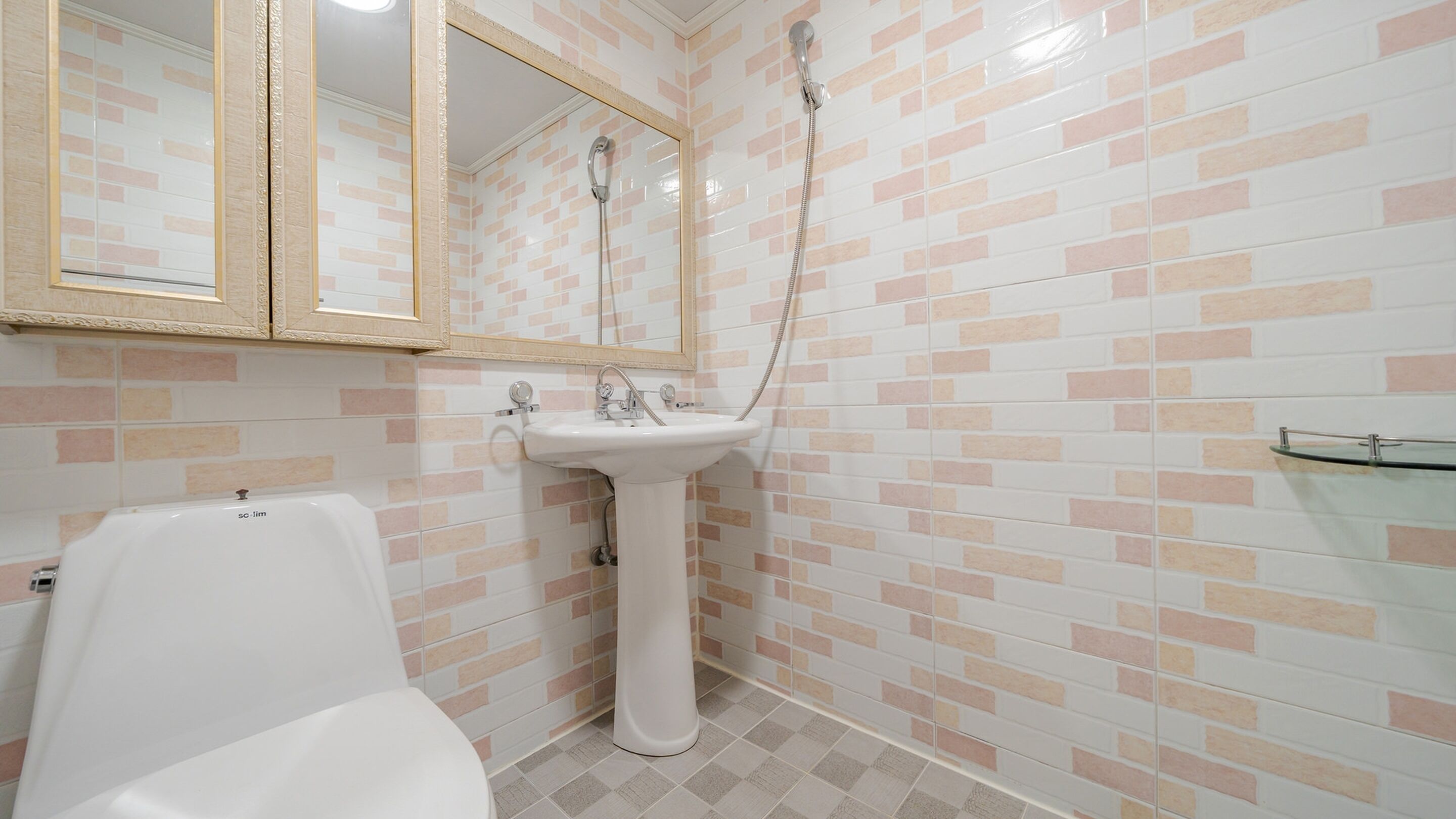 Un baño con lavamanos blanco, espejo y ducha.