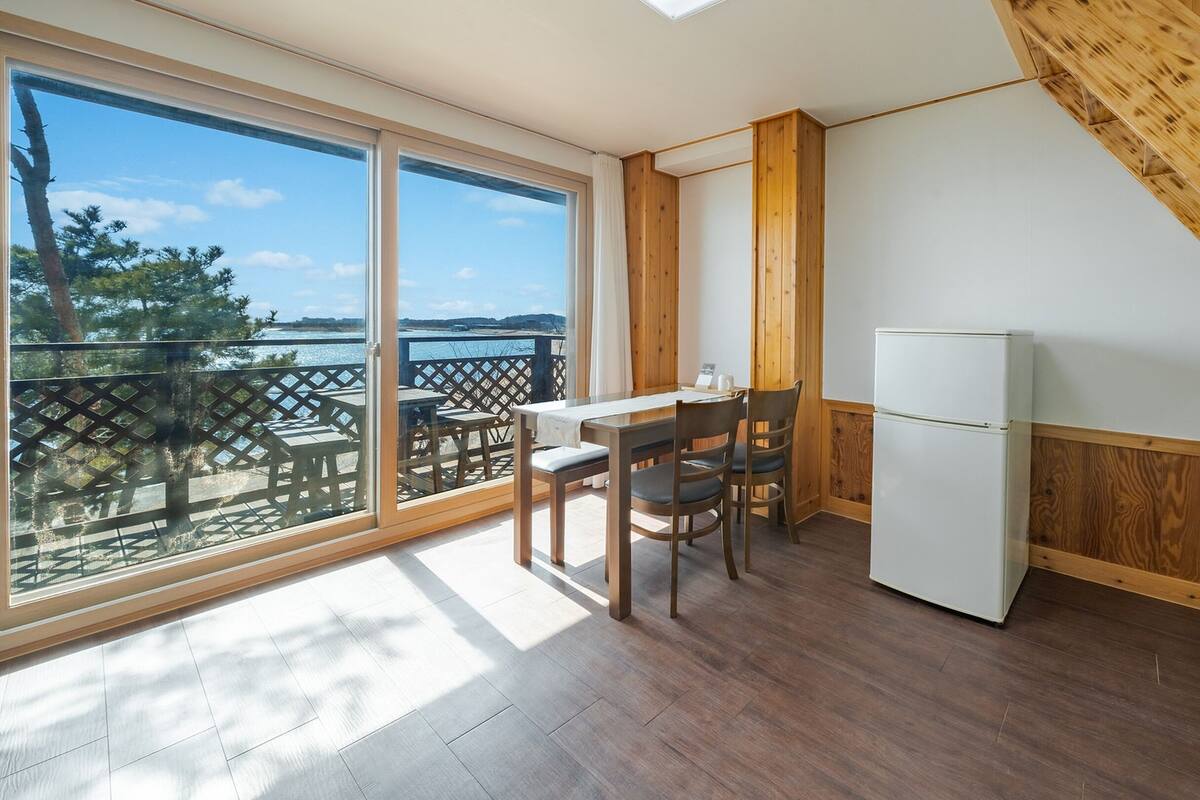 A kitchen with a dining area, large windows, and a view of the outdoors.