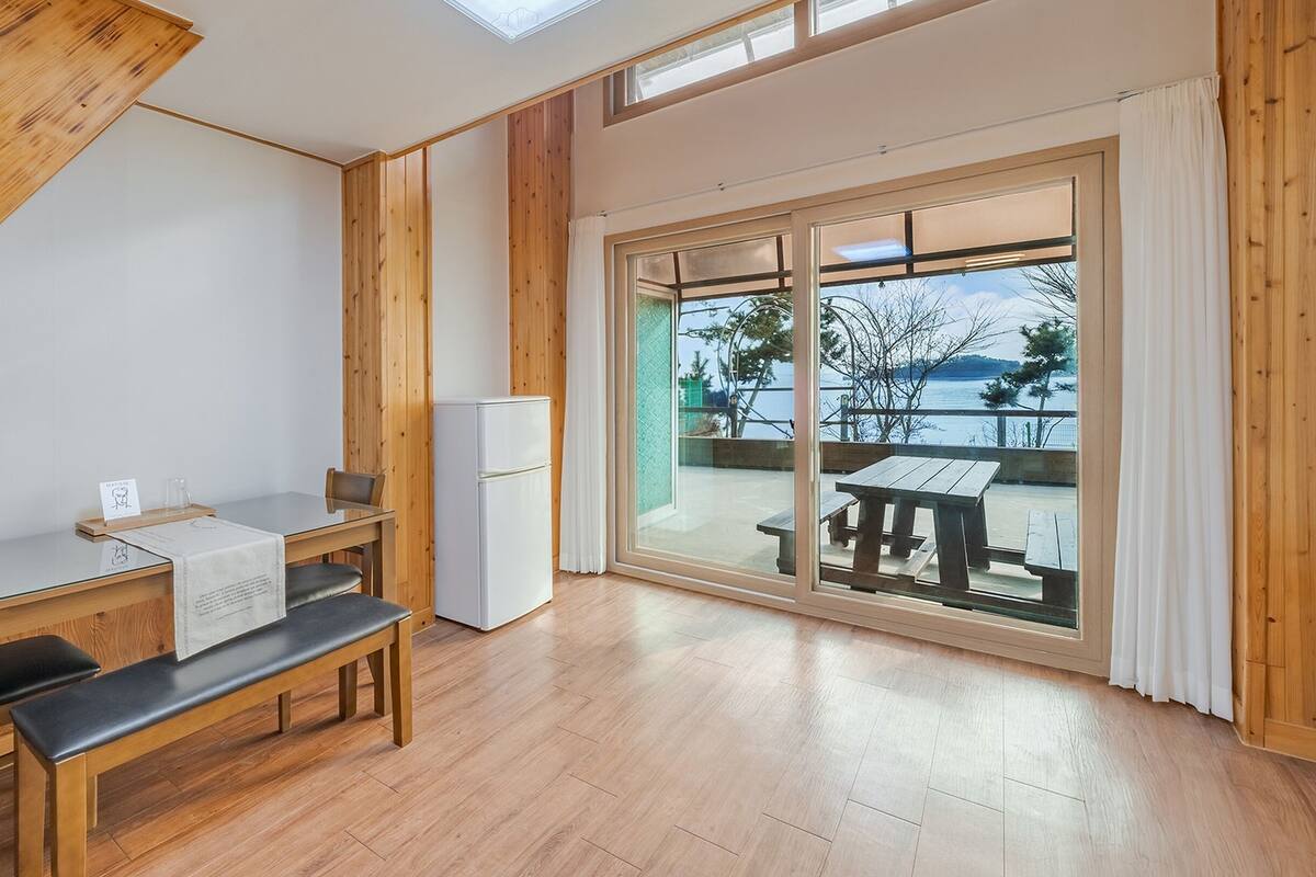 A modern kitchen with a wooden table, bench, and a refrigerator.