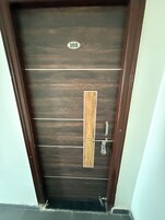 Una puerta de madera oscura con un panel vertical de madera y un tirador de metal.