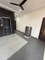 Un pasillo amplio con ventilador de techo, refrigerador y una puerta con reja de metal.