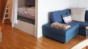 A loft bedroom with a bunk bed, a blue sofa, and a staircase. - Sea view on an island - 20 meters from the bay, 250 meters from the port (Västra Götalands län)
