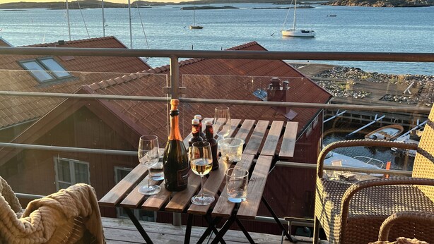 A wooden deck with a table set for dining, overlooking a calm sea with boats. - Sea view on an island - 20 meters from the bay, 250 meters from the port (Västra Götalands län)
