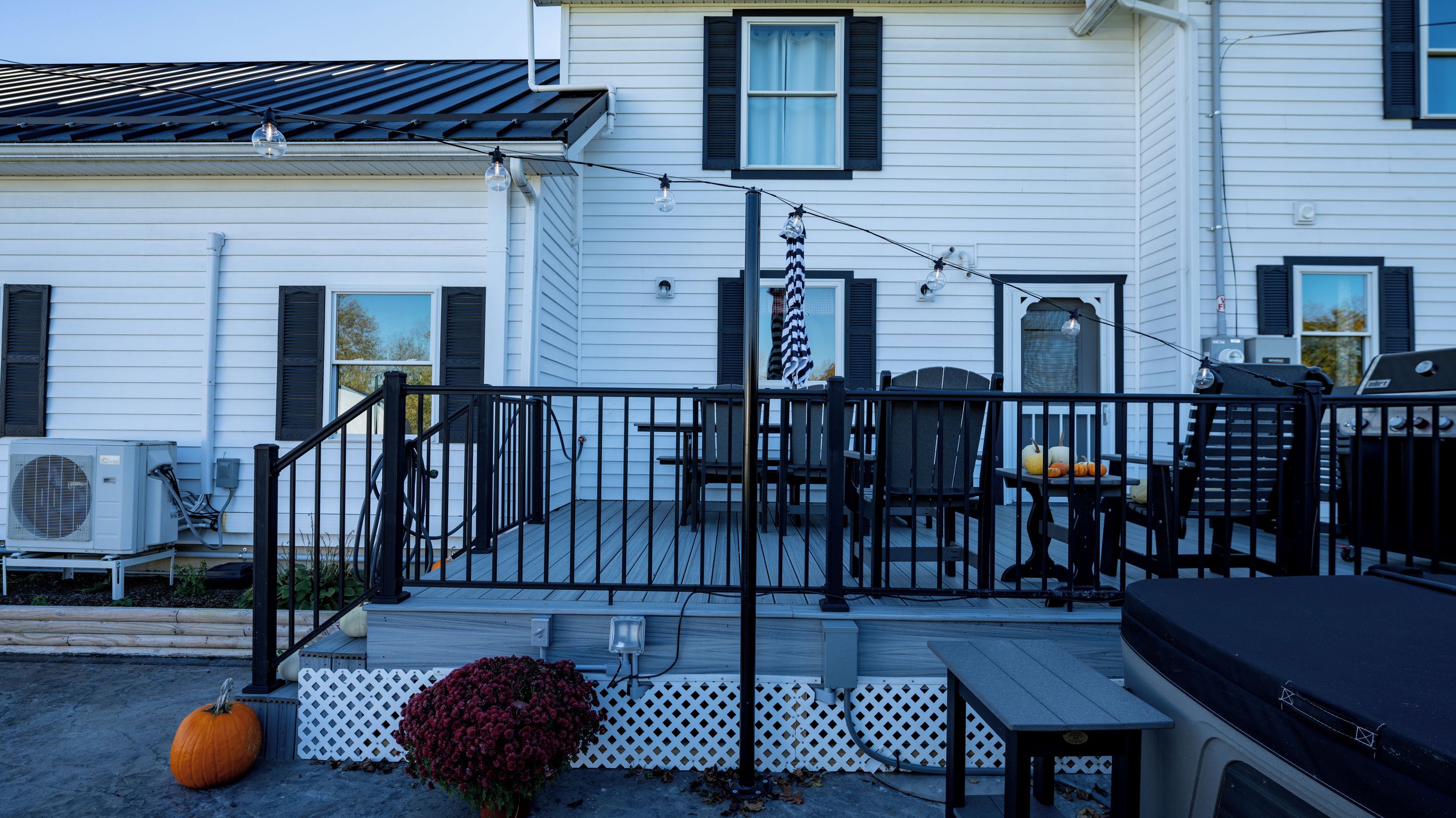 Une terrasse résidentielle aménagée avec du mobilier d’extérieur, un barbecue et des éclairages décoratifs.