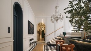 Ein Flur mit Schachbrettmuster, einer Treppe, einem Chandelier und einer Pflanze.