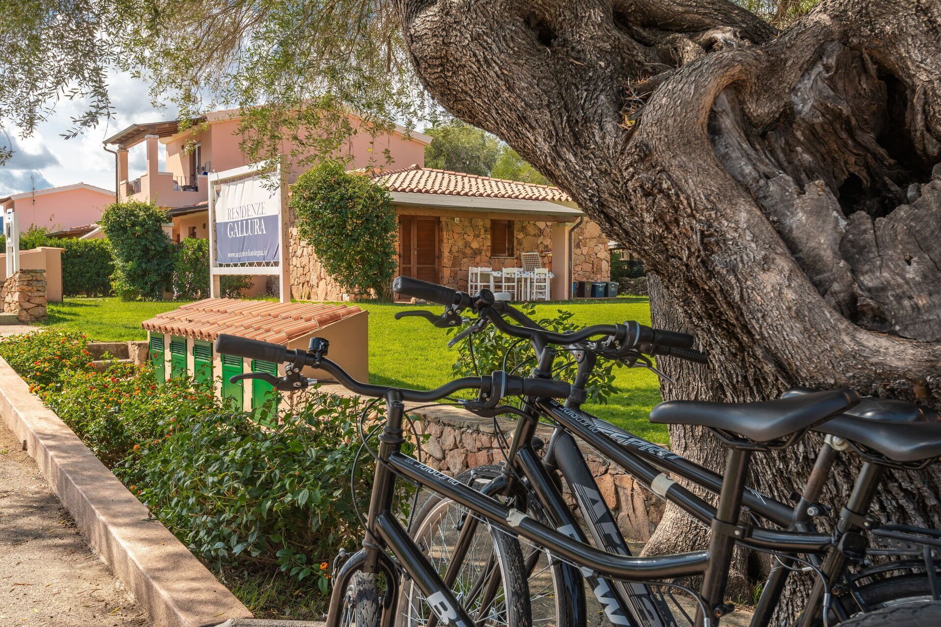 A bicycle parked in front of a building with a stone facade and a sign that reads "RESIDENZE GALLURA".