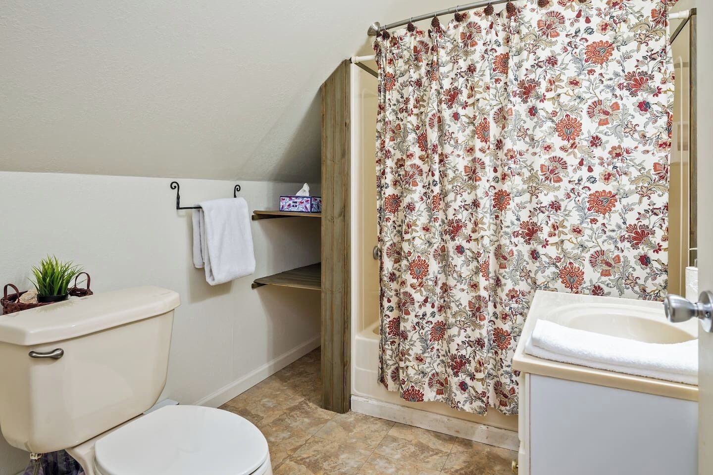 Ein Badezimmer mit Toilette, Waschbecken, Duschvorhang und einem Handtuchhalter mit Handtuch.