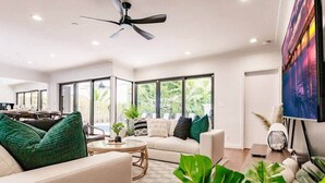 Un salon spacieux doté d’un ventilateur de plafond, de grandes fenêtres, d’un canapé et d’une table basse.