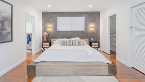 Une chambre moderne avec un grand lit, des lampes de chevet, une fenêtre avec des stores et une armoire.