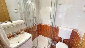 A bathroom with a glass-enclosed shower, a sink, a toilet, and a mirror. - Studio Apartman Kira 5 (Dramalj)