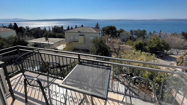 A balcony with metal railings, outdoor furniture, and a view of the sea and distant mountains. - Studio Apartman Kira 5 (Dramalj)