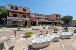 A building with a covered outdoor seating area, potted plants, and a stone pathway. - Cosy apartment for 4 people with A/C, WIFI, TV and panoramic view, close to Olbia (Golfo Aranci)