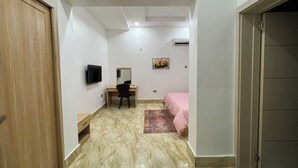 Ein Schlafzimmer mit einem Bett, einem Schreibtisch, einem Sessel, einem Fernseher und einem Bild an der Wand.