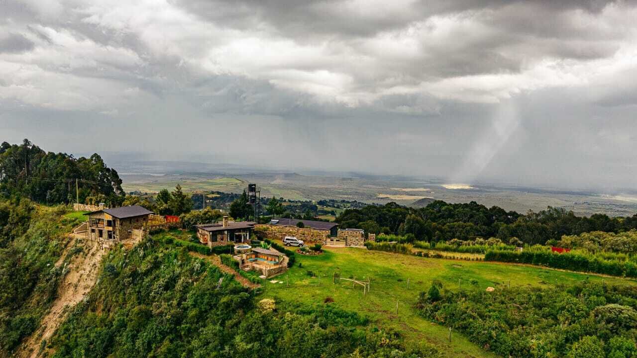 Ein ländliches Anwesen mit mehreren Gebäuden, darunter ein Haupthaus und verschiedene Nebengebäude, umgeben von üppiger Vegetation und einer hügeligen Landschaft.