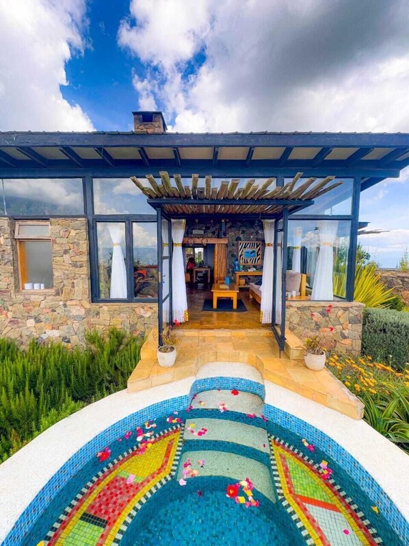 A modern house with a stone exterior, a glass-enclosed patio, and a mosaic-tiled swimming pool. - ol eburru cottage naivasha (Naivasha)