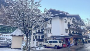 A multi-story hotel with balconies, a parking area, and a storefront with outdoor seating. - Heart Hotel Nordstern (Mayrhofen)