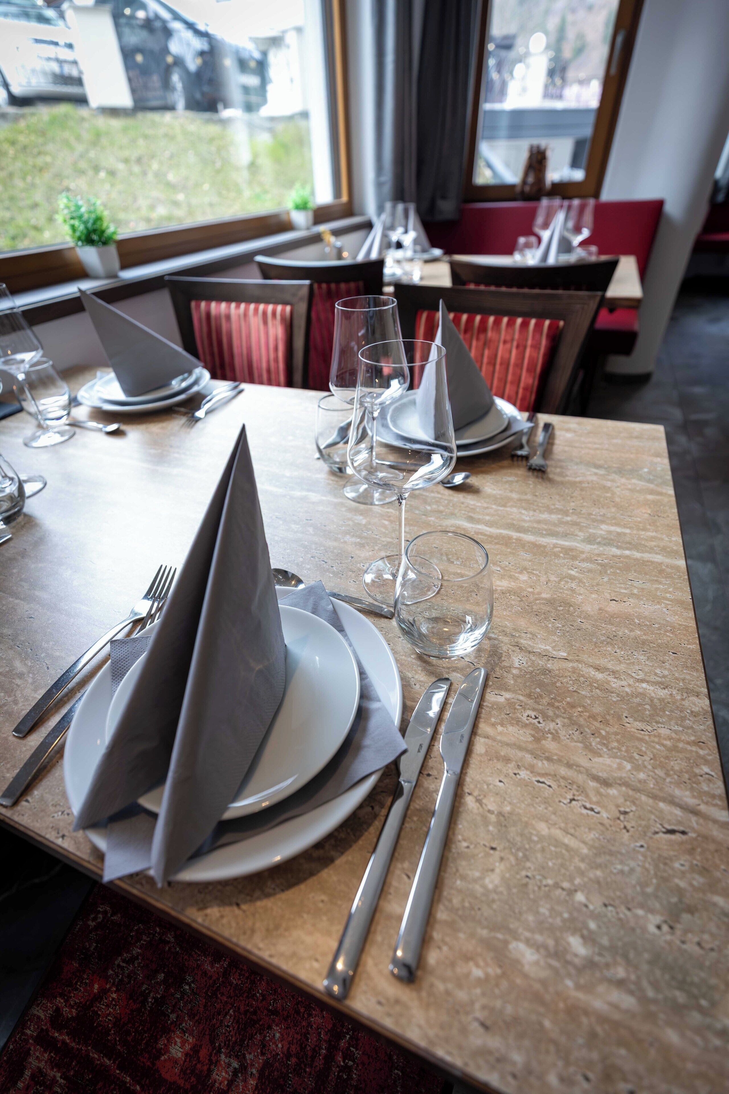 Een gedekte restauranttafel met borden, bestek en servetten.