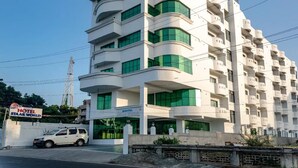A multi-story hotel with balconies, a car parked in front, and a clear sky. - HOTEL STAAR WORLD (Nagercoil)