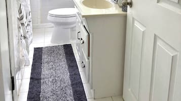 A compact bathroom with a toilet, sink, and shower area.