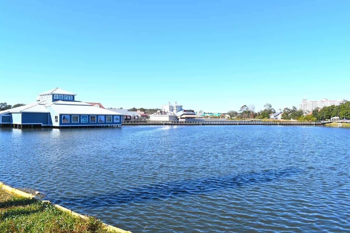 Ein Hotel am Wasser mit einer Anlegestelle, die sich ins Wasser erstreckt, bewölkter Himmel und Gebäuden im Hintergrund.