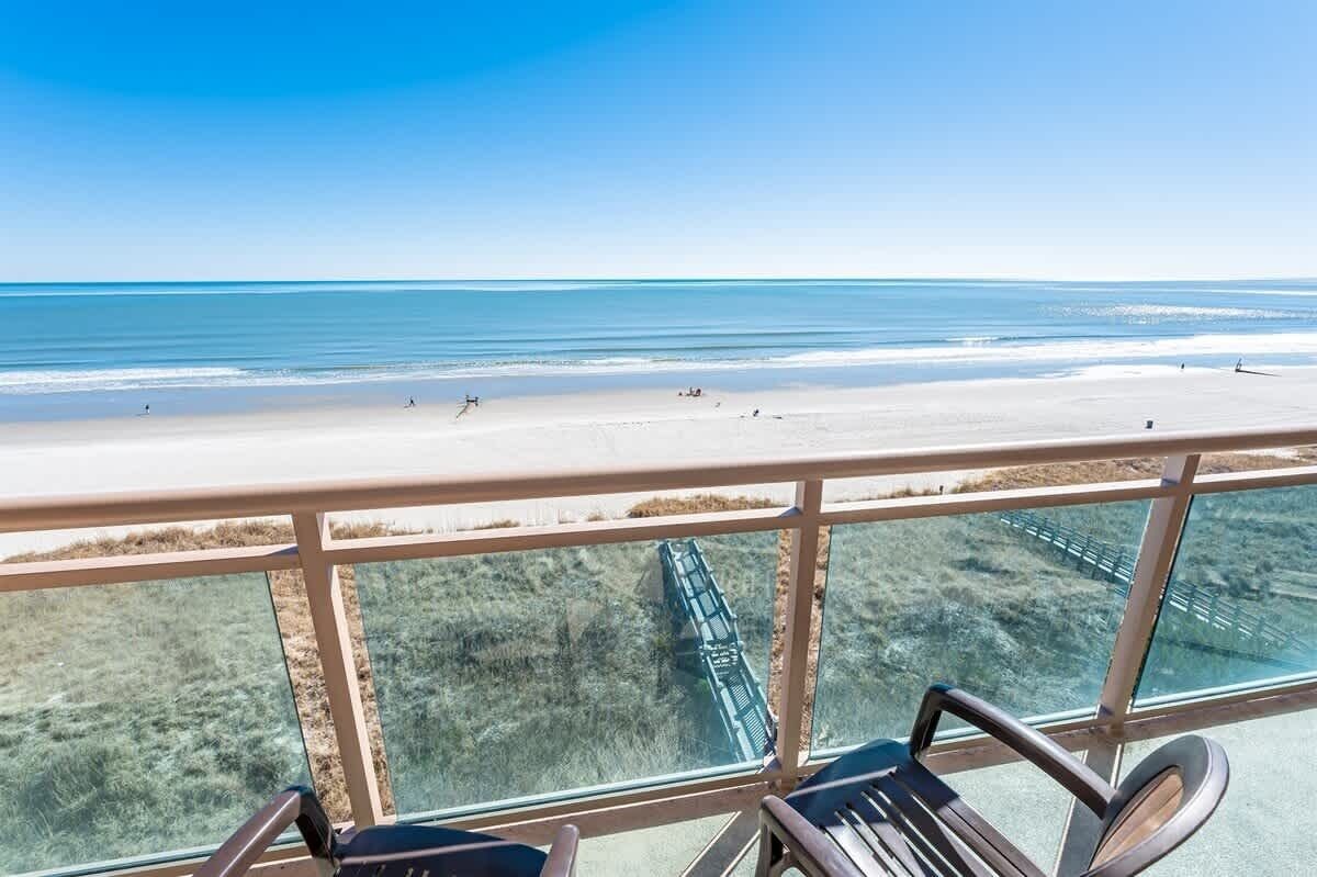 Un balcon offrant une vue dégagée sur une plage et un pont.