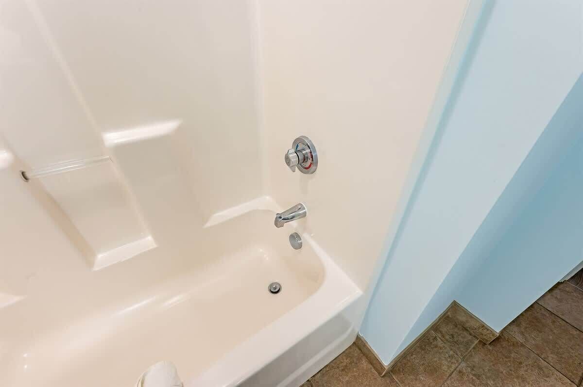 Un coin de salle de bain avec une baignoire blanche, un robinet chromé et un panneau de commande fixé au mur.